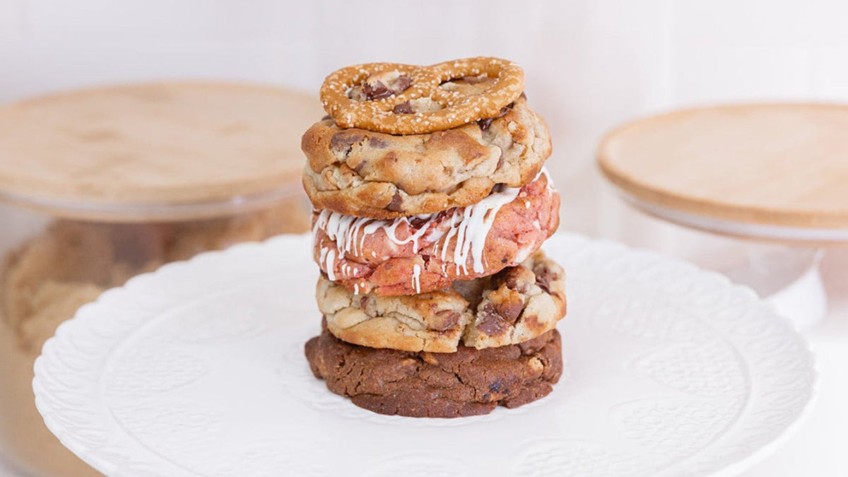 Stack of cookies on a white plate with jars in the background
